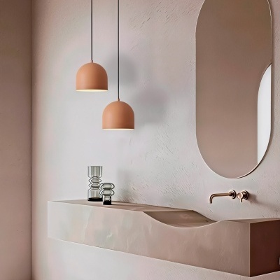 Lavatório moderno bege com espelho oval, torneira dourada e duas lâmpadas terracota suspensas