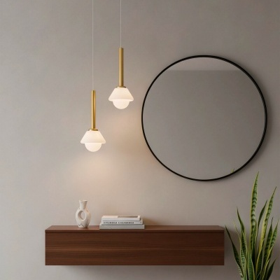 Candeeiros pendentes dourados e branca, prateleira flutuante em madeira com vaso e livros, espelho redondo preto e planta em vaso de barro.