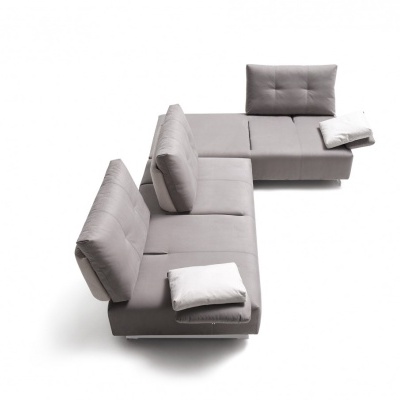 Sofá cinzento claro em forma de L com almofadas brancas, assentos e encostos almofadados