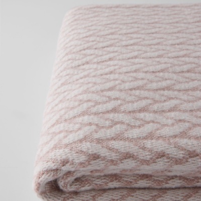 Manta dobrada em padrão geométrico rosa claro e branco