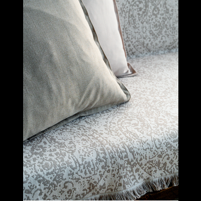 Sofá com estofado floral cinza e branco e almofadas cinza aveludado e branca