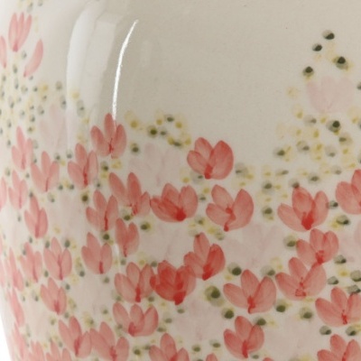 Vaso de cerâmica com padrão floral cor-de-rosa e verde sobre fundo creme
