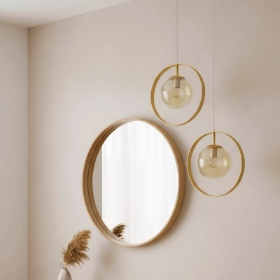 Espelho redondo de madeira clara e lâmpadas pendentes douradas em ambiente minimalista