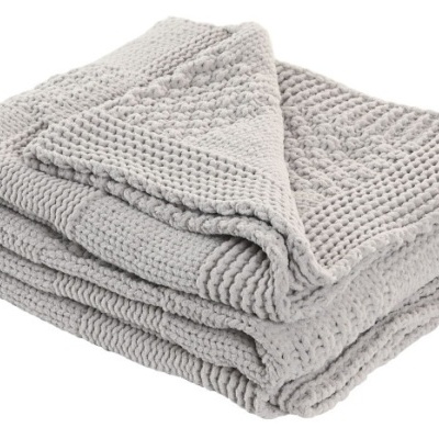 Manta cinzenta de tecido tricotado com padrão texturizado dobrada.