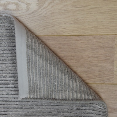Tapete cinzento texturado sobre chão de madeira clara
