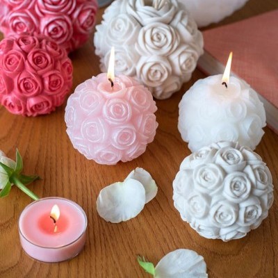 velas esféricas decorativas com padrão de rosas em rosa, branco e cinza sobre mesa de madeira