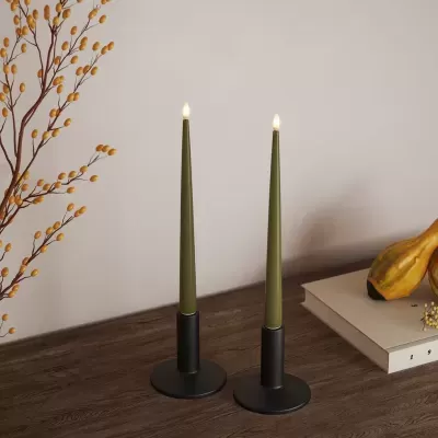 Dois castiçais pretos com velas verdes e decoração de outono