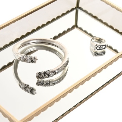 Pulseira e anel de prata com detalhes decorativos em recipiente espelhado com moldura dourada