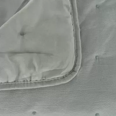 Colcha cinzenta clara com textura felpuda e botões decorativos