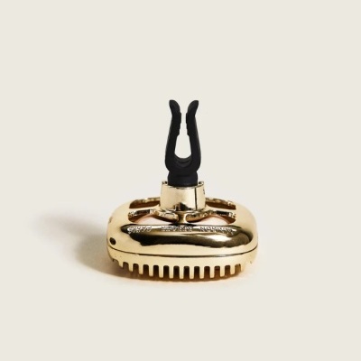 Acessório de guitarra metálico dourado com peça preta em forma de garra