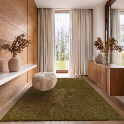 Entrada de casa com tapete verde, cortinas bege, pufe redondo creme e móveis de madeira