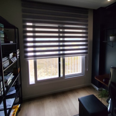 Estores cinzentos em janela de escritório com chão de madeira e estante negra