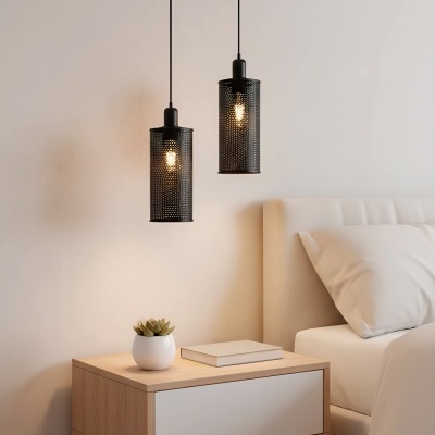 Mesa de cabeceira em madeira clara com gaveta branca ao lado de cama com cabeceira creme e luzes pendentes pretas perfuradas.