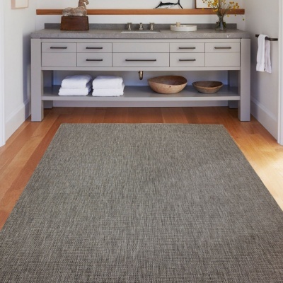 Tapete cinza em chão de madeira à frente de móvel cinza com toalhas e tigelas de madeira