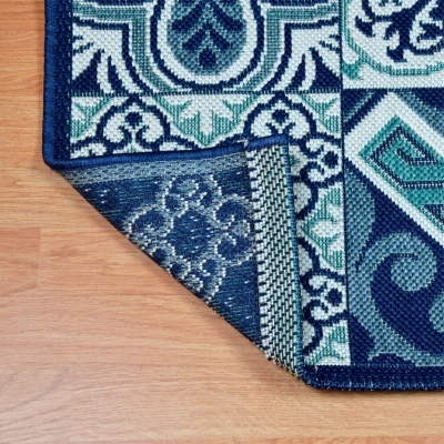 Tapete com padrão geométrico em azul, verde e branco numa superfície de madeira.