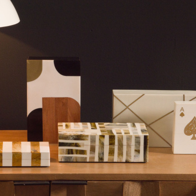 Mesa com lâmpada e caixas decorativas em branco, castanho e dourado.