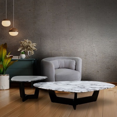 Conjunto de mesas de centro em mármore branco com pés pretos, poltrona cinza e planta em vaso branco junto a móvel verde escuro