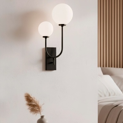 Candeeiro de parede preto com lâmpadas esféricas brancas e mesa de madeira com vaso cinza e planta seca