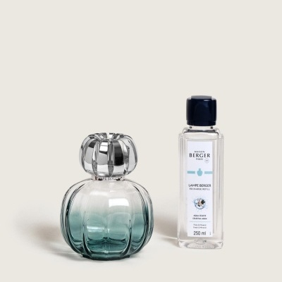 Difusor de fragrância em vidro azul esverdeado com tampa prateada ao lado de garrafa de recarga Maison Berger