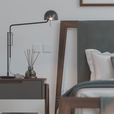 Móvel de cabeceira com candeeiro e decoração ao lado de cama com cabeceira estofada cinzenta