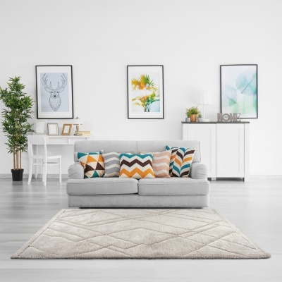 Sala moderna com sofá cinza, almofadas coloridas, tapete creme, móveis brancos e quadros na parede.