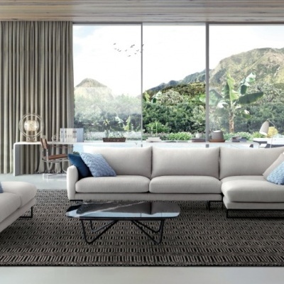 Sala de estar com sofás cinza, poltrona azul, mesa preta e grandes janelas com vista