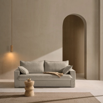 Sofá cinza claro com almofadas, mesa de apoio em madeira, candeeiro pendente e arco de parede neutra