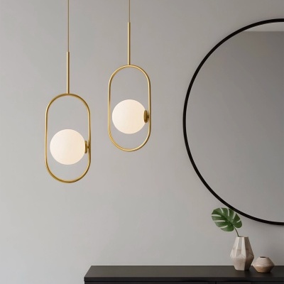 Luzes pendentes douradas com globos de vidro e móvel preto com espelho redondo