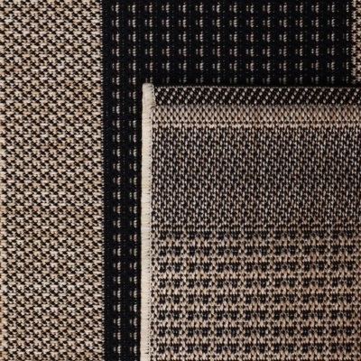 Tapete têxtil preto e bege com padrões geométricos dobrado