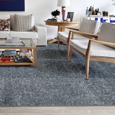 Tapete cinza denso numa sala de estar com móveis de madeira clara e estofados brancos