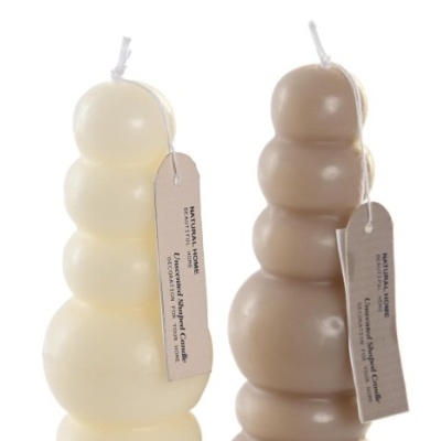 Duas velas decorativas em forma de bolhas, uma branca e outra bege, com etiquetas penduradas.