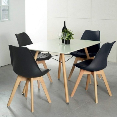 Mesa branca quadrada com pernas de madeira e quatro cadeiras pretas com pés de madeira