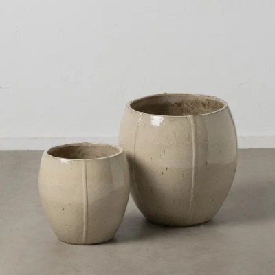 Dois vasos de cerâmica bege claro com acabamento brilhante em chão cinzento.
