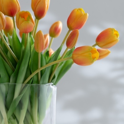 Buquê de tulipas amarelas e laranja em vaso de vidro.