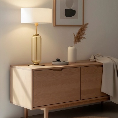 Aparador de madeira clara com candeeiro, jarro branco e decoração minimalista num ambiente interior