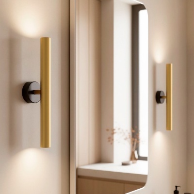 Espelho retangular com barras de luz douradas e torneira dourada numa casa de banho moderna.