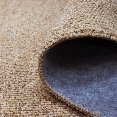 Tapete bege com trama grossa e base antiderrapante cinza, detalhe da borda dobrada.