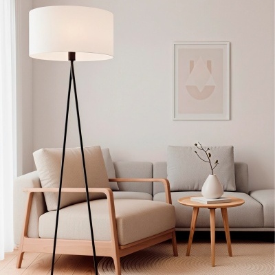 Lâmpada de pé preta com abajur branco numa sala com poltrona e mesa de madeira clara