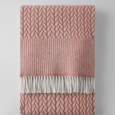 Manta rosa e branca com padrão de malha e franjas