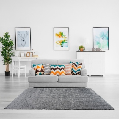 Sofá cinzento com almofadas coloridas e tapete cinzento numa sala de estar moderna