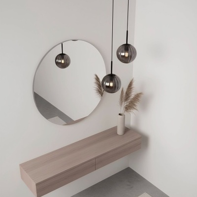 Espelho redondo, luzes pendentes com abajures esféricos de vidro fumado e móvel suspenso de madeira clara com vaso branco e ramos secos