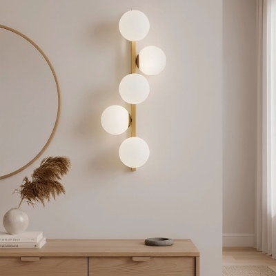 Lâmpada de parede de cinco globos brancos com estrutura dourada sobre parede branca