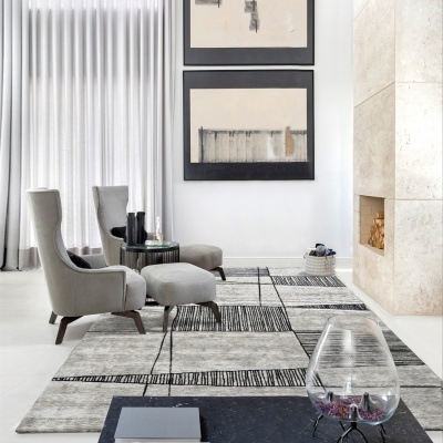 sala com poltronas cinza, tapete geométrico e lareira de mármore