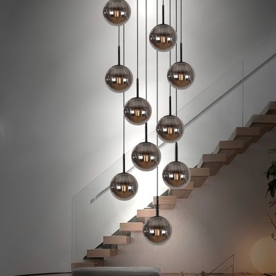 Candeeiros suspensos em vidro fumado em espaço de interior moderno com escada e sofás cinza