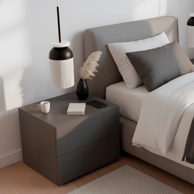 Mesa de cabeceira cinzenta com objetos decorativos ao lado de cama com roupa de cama branca e cinzenta