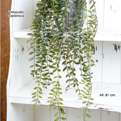 Planta artificial pendente em vaso cerâmico cinzento numa prateleira branca