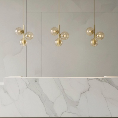 Candeeiros dourados com globos de vidro pendentes sobre balcão de mármore branco
