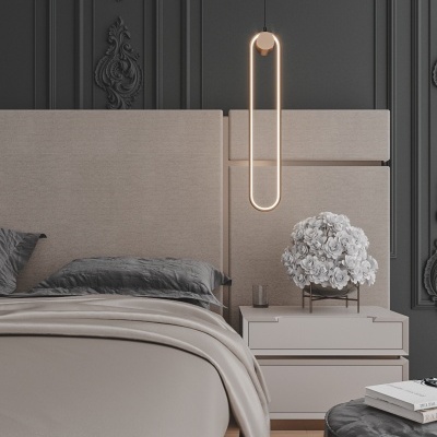 Quarto com cabeceira estofada bege, candeeiro suspenso LED oval dourado, mesa de cabeceira branca com flores brancas e parede escura decorativa