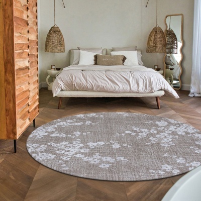 Quarto com cama, candeeiros pendentes, tapete redondo floral e móvel em madeira