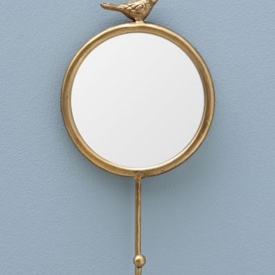 Espelho redondo dourado com pássaro e gancho pendurado na parede azul
